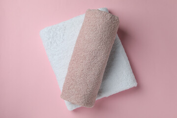 Clean folded towels on pink background, top view