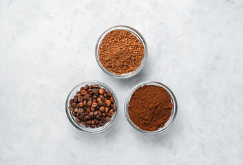 Three cups with different types of coffee on a gray background.