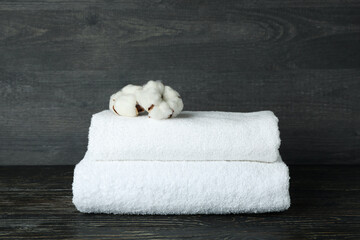 Clean folded towels with cotton on wooden background, close up