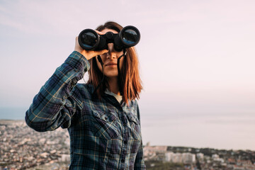 Woman considering natural landscape with binoculars.