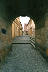 Arch passage on a small old street  with a cobblestone and the walls  are lined with stone limestone, ancient Bavarian city -
Bayreuth, Upper Franconia, Bavaria, Europe, Germany, vertical town image