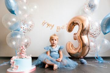 Birthday of a little blonde girl. Child in festive balloons. 
