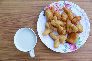 Deep fried dough sticks in dish and cup of soybean milk isolated on wooden background closeup.