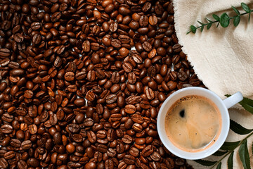 Cup of coffee with beans on table, top view