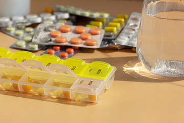 Glass of water and pills on the background of various medicines on the table