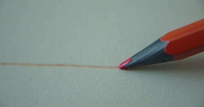 Graphite orange color pencil draws a straight line on a white background paper, special paper for the artist, macro shot. Man's lines. Concept drawing, art