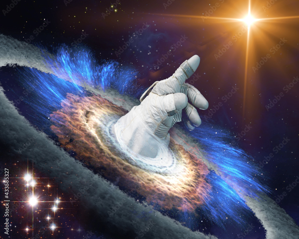 Wall mural astronaut hand in gloves points with finger to a shining star in space through a black hole portal. 