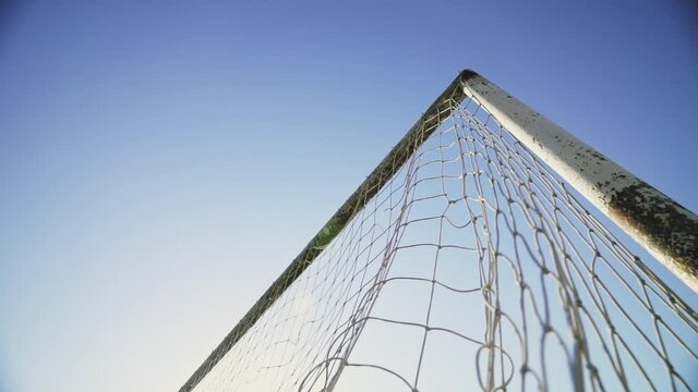 Football concept. The ball hits the corner of the goal. The footballer scores a goal. Winning the championship. Beautiful goal against the blue sky. Bottom view