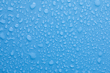 Water drops on blue background. Drops of water on surface. Macro photo. Splash pattern.