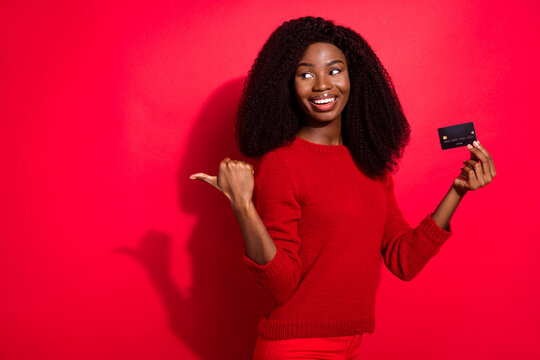 Photo of young afro girl look point finger empty space happy positive smile bank card advert recommed isolated over red color background