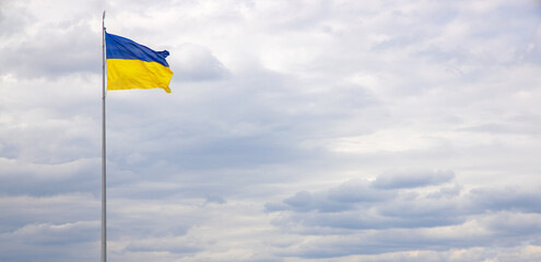 Ukraine national flag against a blue sky. Banner for text about the freedom and independence of country.