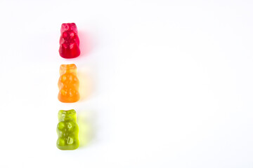 Three gummy bears in colours of traffic lights lined up vertically, isolated on white background with copy space - obrazy, fototapety, plakaty