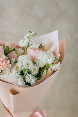 Bouquet of white freesias, carnations and chrysanthemums with pink roses and carnations in a pink package with a ribbon. Summer background