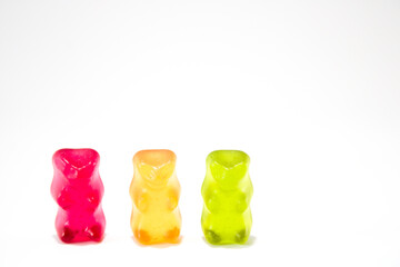 Close up of three gummy bears in line, in traffic lights colours, isolated on white background with copy space