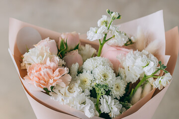 Bouquet of white freesias, carnations and chrysanthemums with pink roses and carnations in a pink package with a ribbon. Summer background