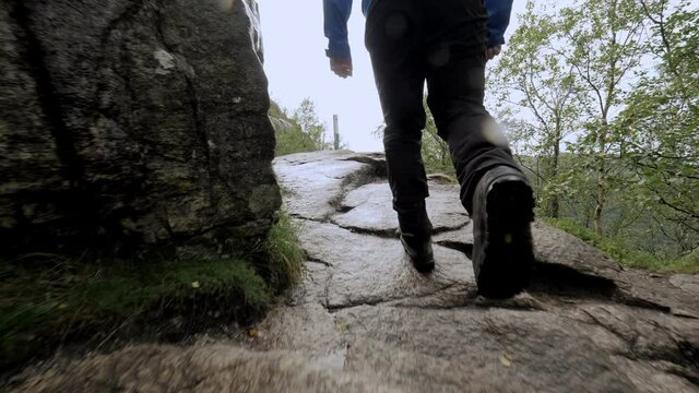 Closeup man legs hiking on natural stones climbing on mountain at tropical rainforest