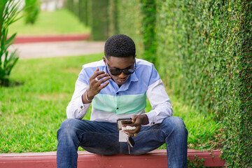image of black guy seated with smart phone-