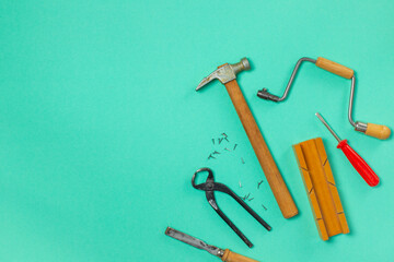 A set of children's vintage carpentry tools are laid out on a green background. Top, Horizontal, copy space