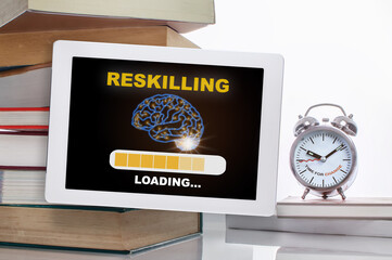 Reskilling loading with brain on digital computer tablet with stack of textbook with time to change words on alarm clock isolated on white background. Technology concept and time management idea