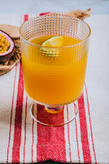 A glass of mango nectar with a slice of lime and cut passion fruit