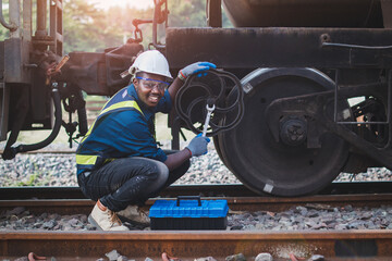 African machine engineer technician wearing a helmet, groves and safety vest is using a wrench to...