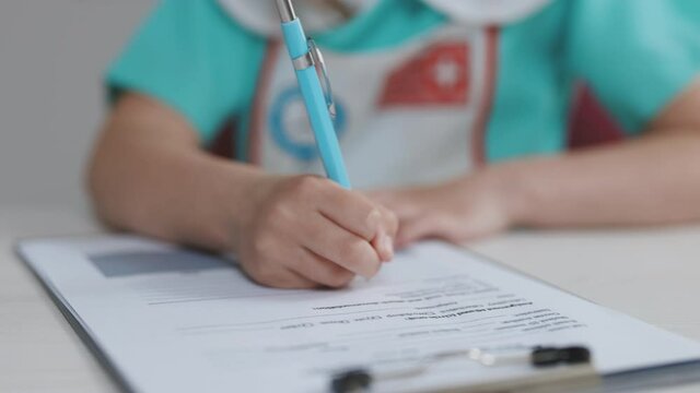 Close Up Wrinkled Little Girl Hands Writing Information In Medical Registration Journal. Cute Little Child Girl Wear Medical Coat Playing Doctor Nurse Future Profession Concept.