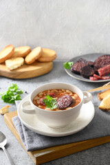 Asturiana traditional fabada with haricot, blood sausage served fresh crispy toast on gray table....