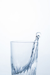 Splash, splashing of water or alcoholic drink in a glass on a white background, close-up