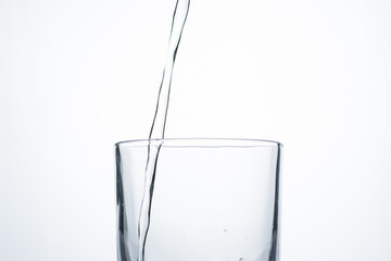 Jet of water or alcohol is pouring into a glass with splashes and bubbles, copy space
