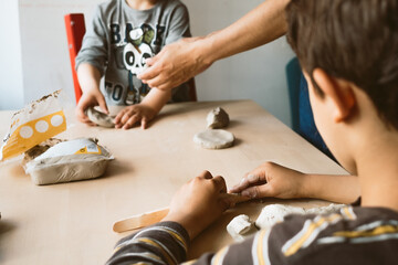 Obraz na płótnie Canvas child playing with clay at home during quarantine. focused boy creating shapes with hands and using creativity and manual skills to mold toy shapes