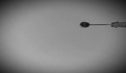 A lamppost against a gray sky. Vignetting effect.