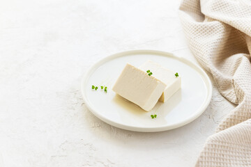 Pieces of tofu cheese with micro greens on a light plate. Horizontal orientation, top view, copy space.
