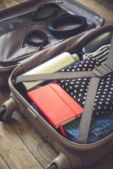 Open suitcase full of clothes isolated on wooden background