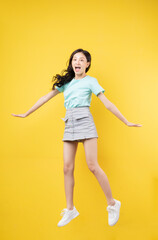 Fototapeta na wymiar Young Asian girl jumping on yellow baclground