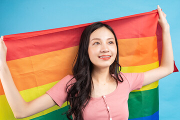 Young Asian woman holding rainbow flag to support LGBTQ+ community