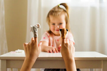 Child playing theater with animal finger puppets. Role-playing games and activities for expressing...
