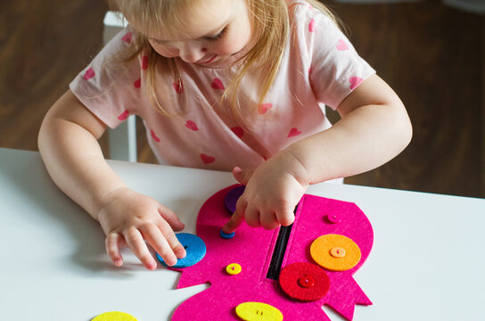 Little Toddler Girl Buttoning A Montessori Toy. Practical Life Skills, Care Of Self, Early Education, Activities And Toy To Develop The Dexterity Of Child Fingers, Practical Life, Learning Colors.  