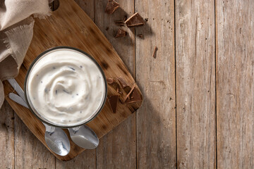 Stracciatella yogurt in transparent bowl on wooden table. Top view. Copy space