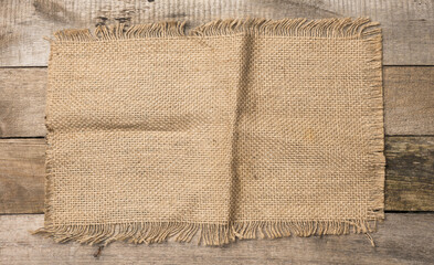 brown burlap fragment on gray wooden background,