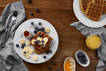 Oatmeal Belgian waffles topped with banana and blueberry on rustic wooden table. Healthy breakfast diet recipe
