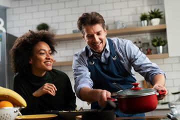 Happy smiling couple cooking together. Husband and wife preparing delicious food..