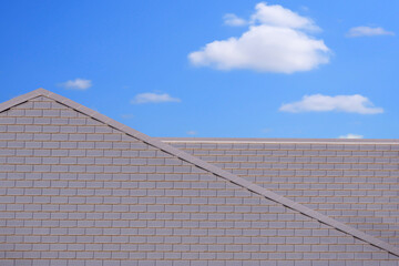 Front view of modern flat concrete gray tile roof against white cloud in blue sky background