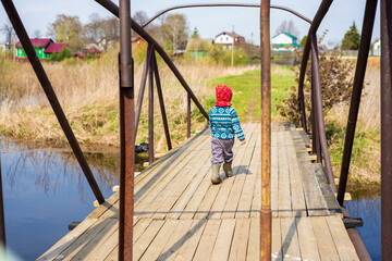 a boy walks on a bridge over the river, early spring