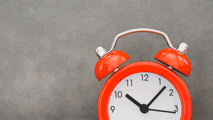 close up of red face analog alarm clock on grunge grey background with copy space, time passing concept