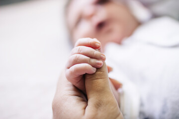 Mom holds her newborn baby by the hand