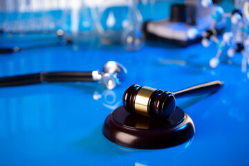 Medical law concept. Gavel and stethoscope on the glass table. Blue light.