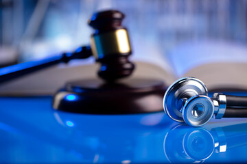 Medical law concept. Gavel and stethoscope on the glass table. Blue light.