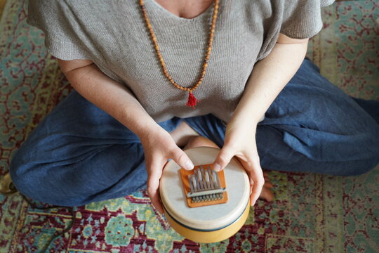 Woman holding and playing a sound healing instrument Sansula for sound healing therapy 