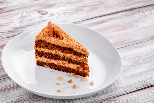 Layered chocolate cake on a white plate on a light wooden background. Photo for the menu and site. Space for text
