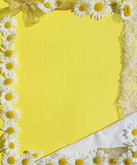 Frame from flowers of daisies, fabric and ruffle, gold ribbon and bow on a yellow background. Frame for birthday, wedding, photo frame to album